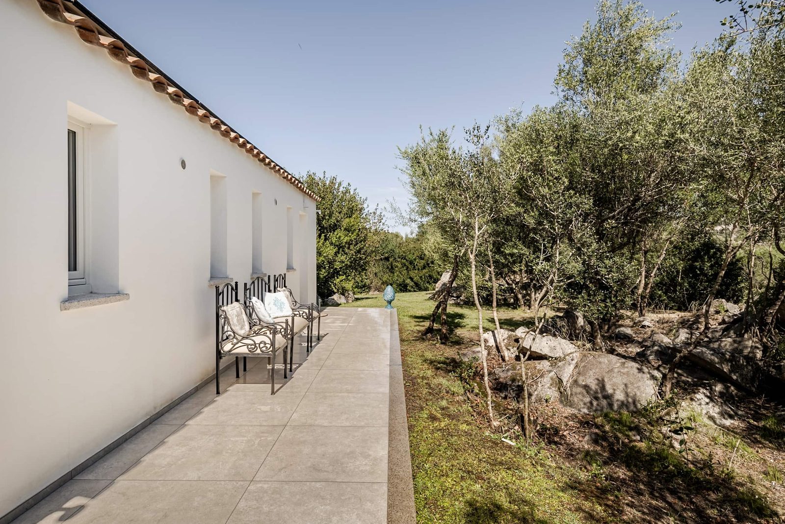 La villa vista dal camminamento esterno, fra gli olivi e le rocce di granito